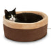 Black and white cat resting in a round heated mocha and beige pet bed